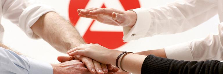 Bild mit aufeinander liegenden Händen und Logo der Arbeitsagentur im Hintergrund