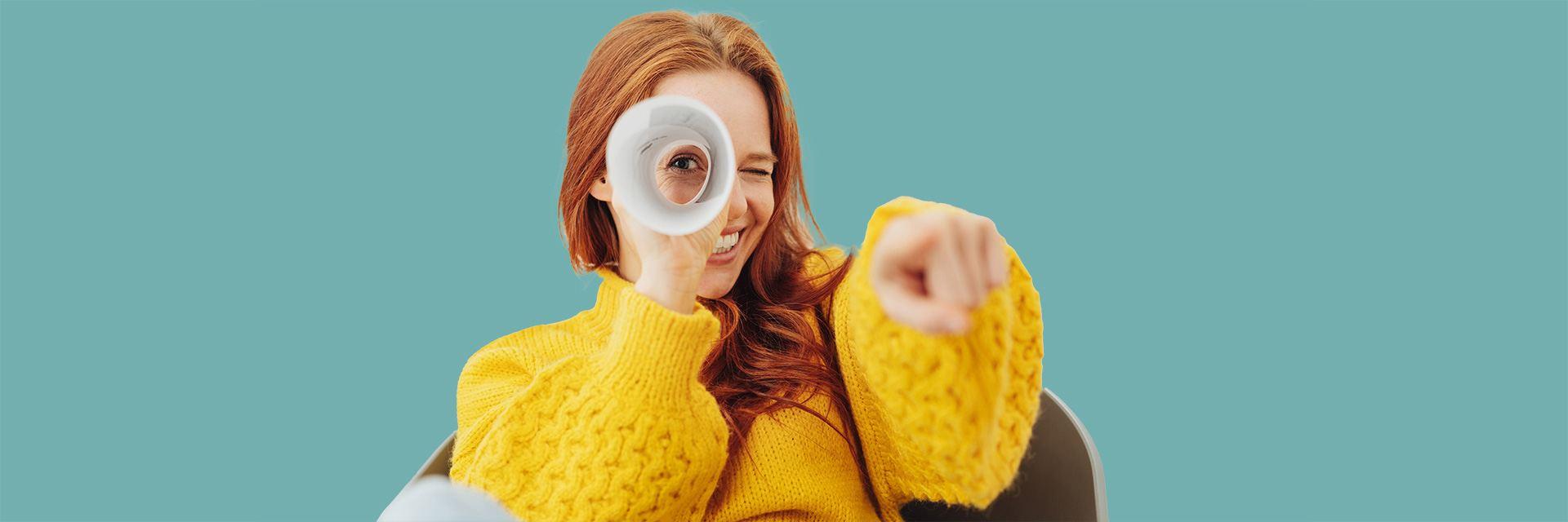 Bild zeigt eine Frau die durch eine Papierrolle schaut